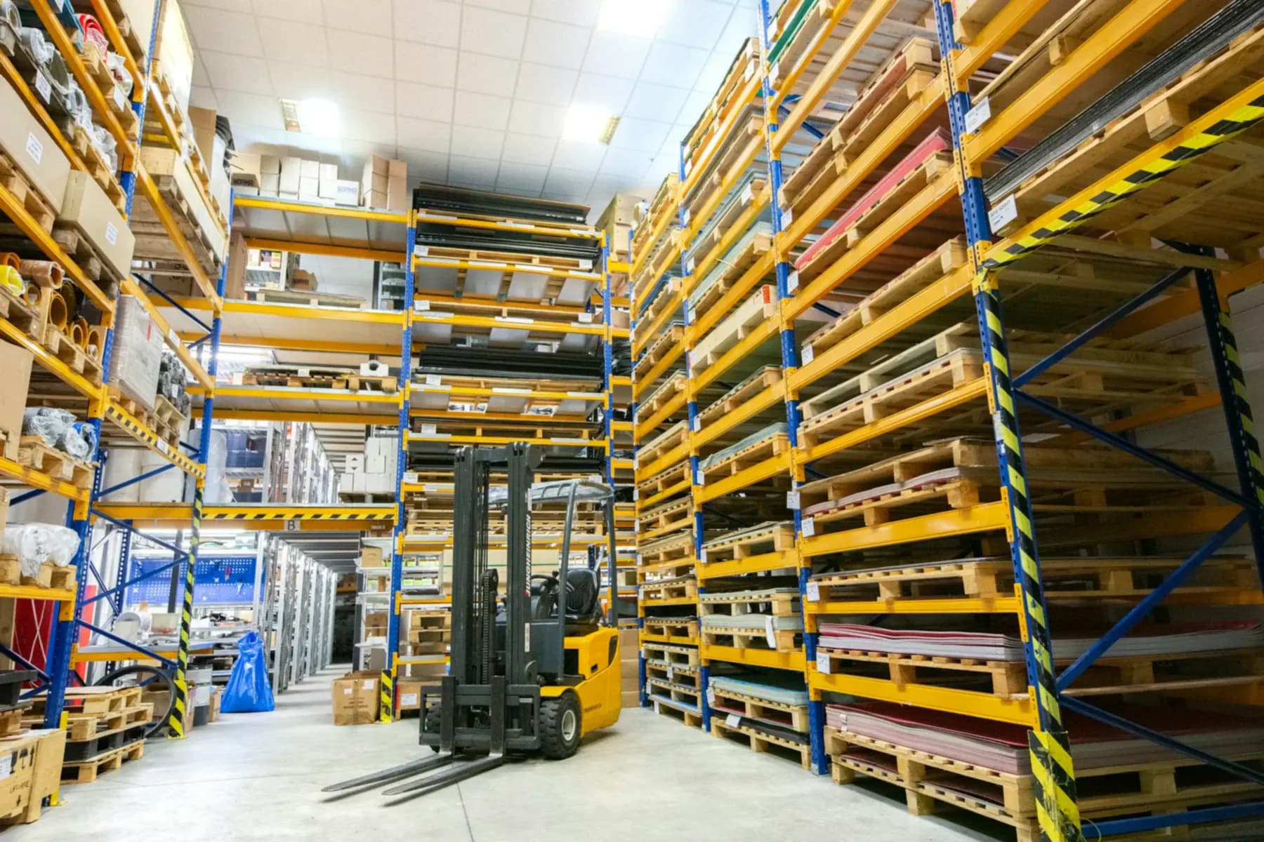 Depósito con racks llenos de pallets y un montacargas